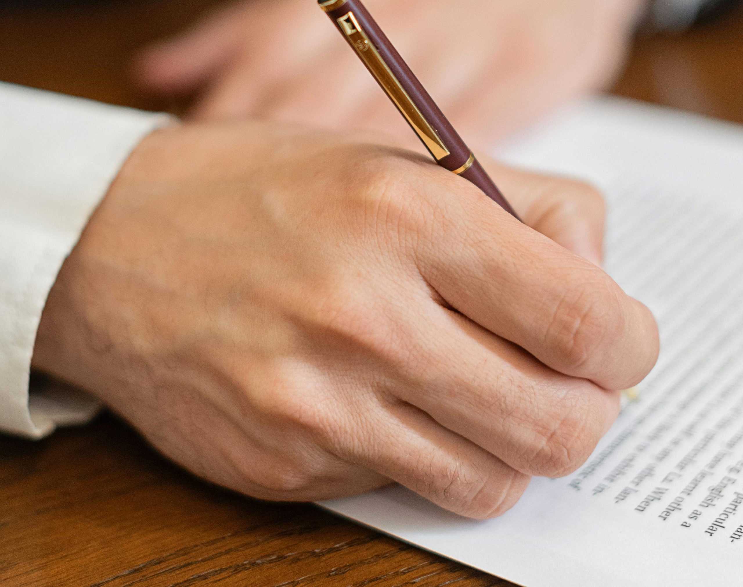 Close-up of a hand signing a business contract with a fountain pen.